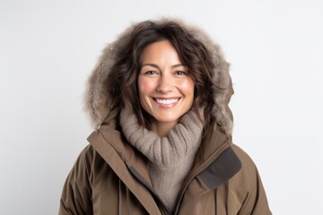Portrait of a joyful woman in her 40s wearing a warm parka while standing against white background
