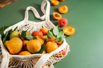 Ripe apricots in a string bag on a single background