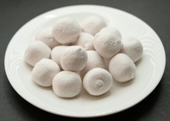Marshmallows in white plate ob dark background.