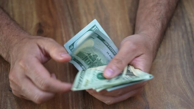Real estate broker counts dollar banknotes from commission check reflecting on hard work of closing major property deal and planning next big sale to sustain business