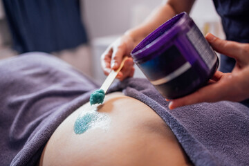 Close-up of the cosmetologist hands and a jar of salt scrub. A dermatologist applies a natural cosmetic produc