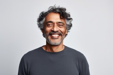 Obraz premium Portrait of a grinning indian man in his 50s showing off a thermal merino wool top while standing against white background
