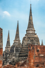 Fototapeta premium Three stupas in Wat Phra Si Sanphet ancient temple in Ayutthaya historical park, Thailand, Asia. Historical Buddhist Chedi architecture on archaelogical site under blue sky. Vertical orientation