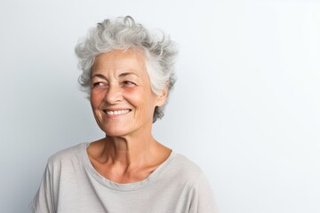 Portrait of a jovial woman in her 70s dressed in a casual t-shirt over white background