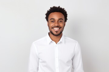 Fototapeta premium Portrait of a satisfied afro-american man in his 20s wearing a classic white shirt in front of white background