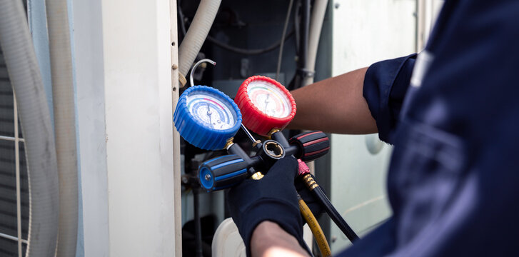 Air conditioning, HVAC service technician using gauges to check refrigerant and add refrigerant,Air Conditioning Repair, repairman on the floor fixing air conditioning system.