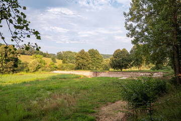 An artificial dam of a pond when it is open and there is no water in the pond.