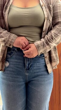 a girl tries to button her jeans, the girl's big belly prevents her from buttoning her jeans, overweight. High quality 4k footage