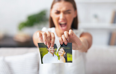 Divorce. Angry Woman Ripping Wedding Photo With Ex-Husband After Breakup Indoor. Selective Focus