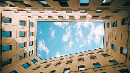 Modern architecture. Symmetrical hole among the walls surrounded by windows with blue sky and white...