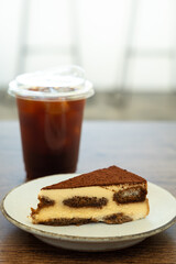 Ice coffee and tiramisu cake on wooden table.