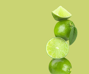 Stacked fresh limes on light green background, space for text