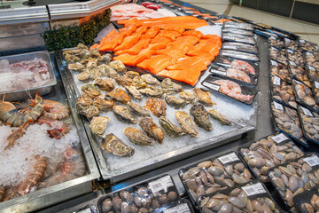 Fresh seafood display with various shrimps, salmon fillet, oysters, clams, shellfish in grocery...
