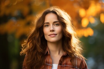 Naklejka premium Portrait of a satisfied woman in her 30s wearing a comfy flannel shirt in background of autumn leaves