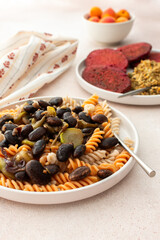 Gluten-free pasta with baked beans and zucchini, paired with beet pancakes topped with sunflower seed hummus. This healthy vegetarian meal is both delicious and nourishing