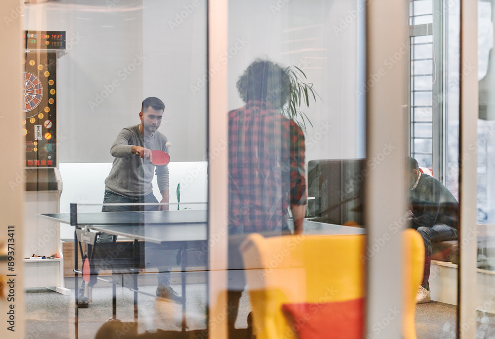 Wall mural  Business colleagues take a break from work to enjoy a game of table tennis, fostering teamwork and camaraderie in the workplace