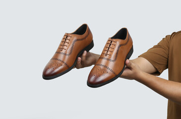 tan leather oxford brogue shoes hold in hand isolated on white background