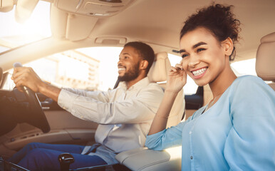 Young african american couple driving in car, travelling together by auto