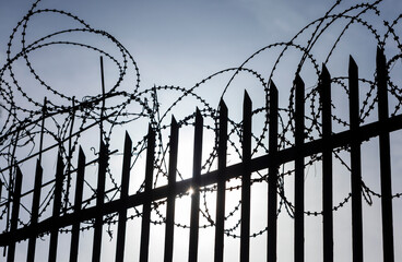 Barbed wire fence silhouette. A barbed wire fence silhouetted against a bright sky.