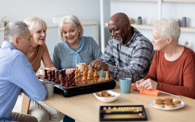 Multiracial senior people men and women in casual playing chess at nursing home, sitting around...