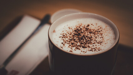 Dark brown granite texture cup cappuccino coffee with cinnamon topping flying isolated on white background. Pastry shop or cafe card element.