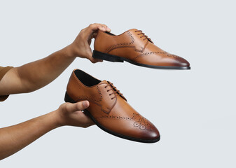 tan leather oxford brogue shoes hold in hand isolated on white background