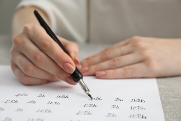 Calligraphy. Woman with fountain pen writing words Reading and Read in Hindi on paper at grey...