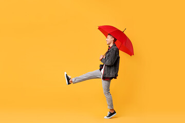 Young man with red umbrella on yellow background, space for text