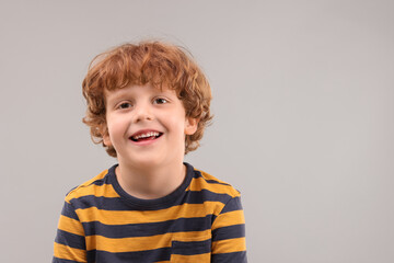 Portrait of cute little boy on grey background, space for text