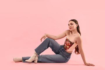 Beautiful woman in stylish corset posing on pink background