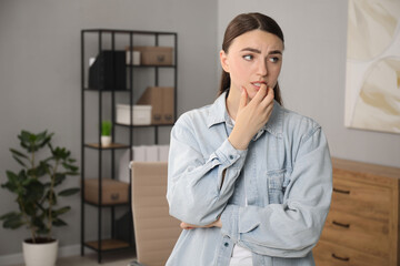 Embarrassed woman in denim jacket in office, space for text