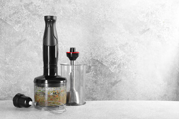 Hand blender kit and mixture of ingredients on light grey table, space for text