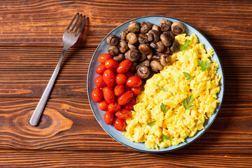 Homemade scrambled eggs with mushrooms and cherry tomatoes
