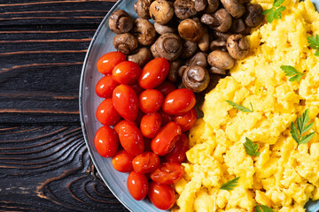Homemade scrambled eggs with mushrooms and cherry tomatoes