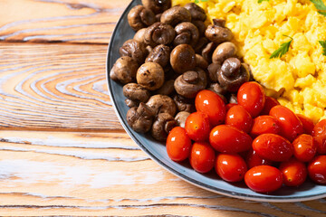 Homemade scrambled eggs with mushrooms and cherry tomatoes