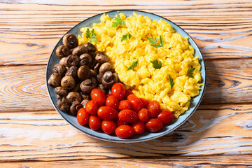 Homemade scrambled eggs with mushrooms and cherry tomatoes