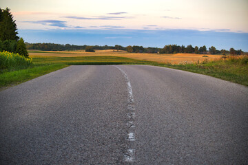 Empty rural road with scenic countryside at sunset