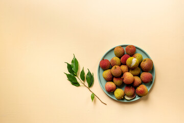 Lychee with green leaf on the plate, top view. Tropical fruits background