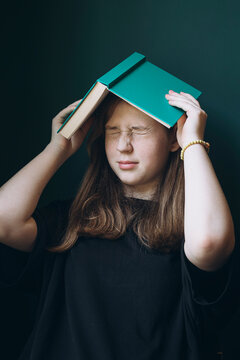 Young girl using book as a hat in a moment of frustration