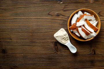 Coconut protein in spoon and bowl of coconut pieces, top view