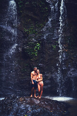 Fototapeta premium Couple, people and happy on waterfall for summer holiday or break to relax, swim and adventure in Thailand. Relationship, nature and smile at river on vacation or journey for bonding with wildlife