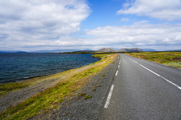 Coastal empty rural road to mountains through tundra in Iceland