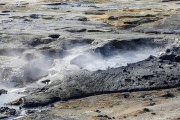Lifeless rocky terrain hot springs with boiling water and steam coming out in Iceland