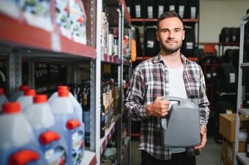 seller man with canister of motor oil in auto store