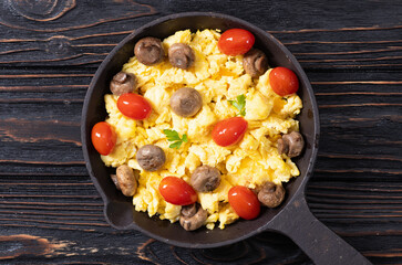 Homemade scrambled eggs with mushrooms and cherry tomatoes