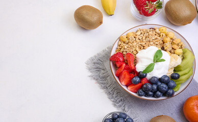 Granola with strawberries, kiwi, banana and blueberries in a round plate