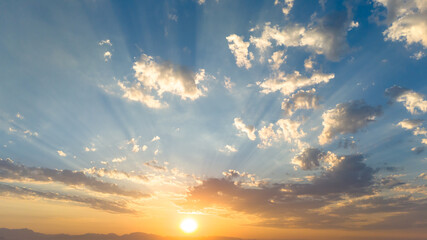 Beautiful sky with bright sun and clouds at sunset with sun beams as a background