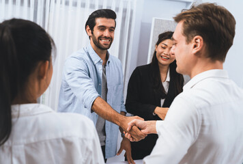 Fototapeta premium Diverse group of office employee worker shake hand after making agreement on strategic business marketing meeting. Teamwork and positive attitude create productive and supportive workplace. Prudent