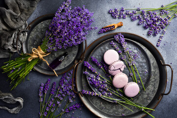 French macarons with lavender flavor and fresh lavender flowers, on a stone plate. Top view.