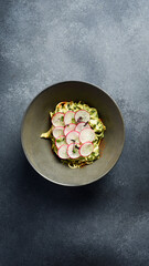 Italian pasta with cheese, pesto sauce and radish. In a plate. Top view.